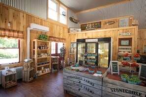Un intérieur rustique avec des murs en bois, un grand réfrigérateur central et divers présentoirs de produits frais.