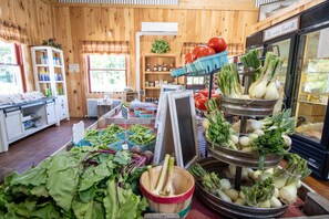 Un intérieur rustique avec des murs en bois, une variété de légumes frais exposés sur des tables et une pancarte indiquant « Soyez les bienvenus ».