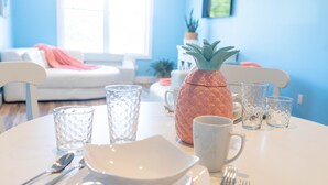 Una mesa de comedor dispuesta con platos, tazones, cubiertos y vasos, con una piña como centro de mesa.