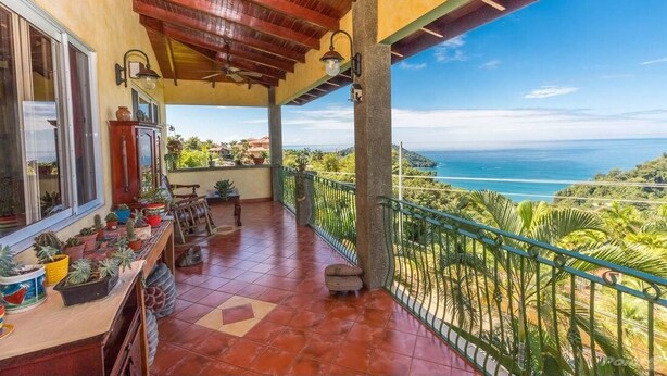 A covered balcony with a view of the ocean, potted plants, and a wooden table. - Villa Sea Forever, Big Ocean View, Heart of Manuel Antonio (Quepos)