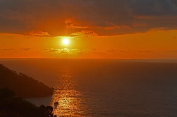 A sunset over a coastal landscape with a view of the sea and a distant shoreline. - Villa Sea Forever, Big Ocean View, Heart of Manuel Antonio (Quepos)