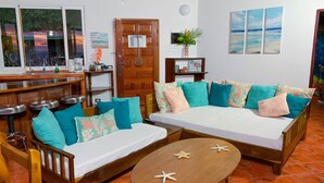 A cozy living room with a sofa set, a wooden coffee table, and a kitchen area with a bar. - Villa Sea Forever, Big Ocean View, Heart of Manuel Antonio (Quepos)