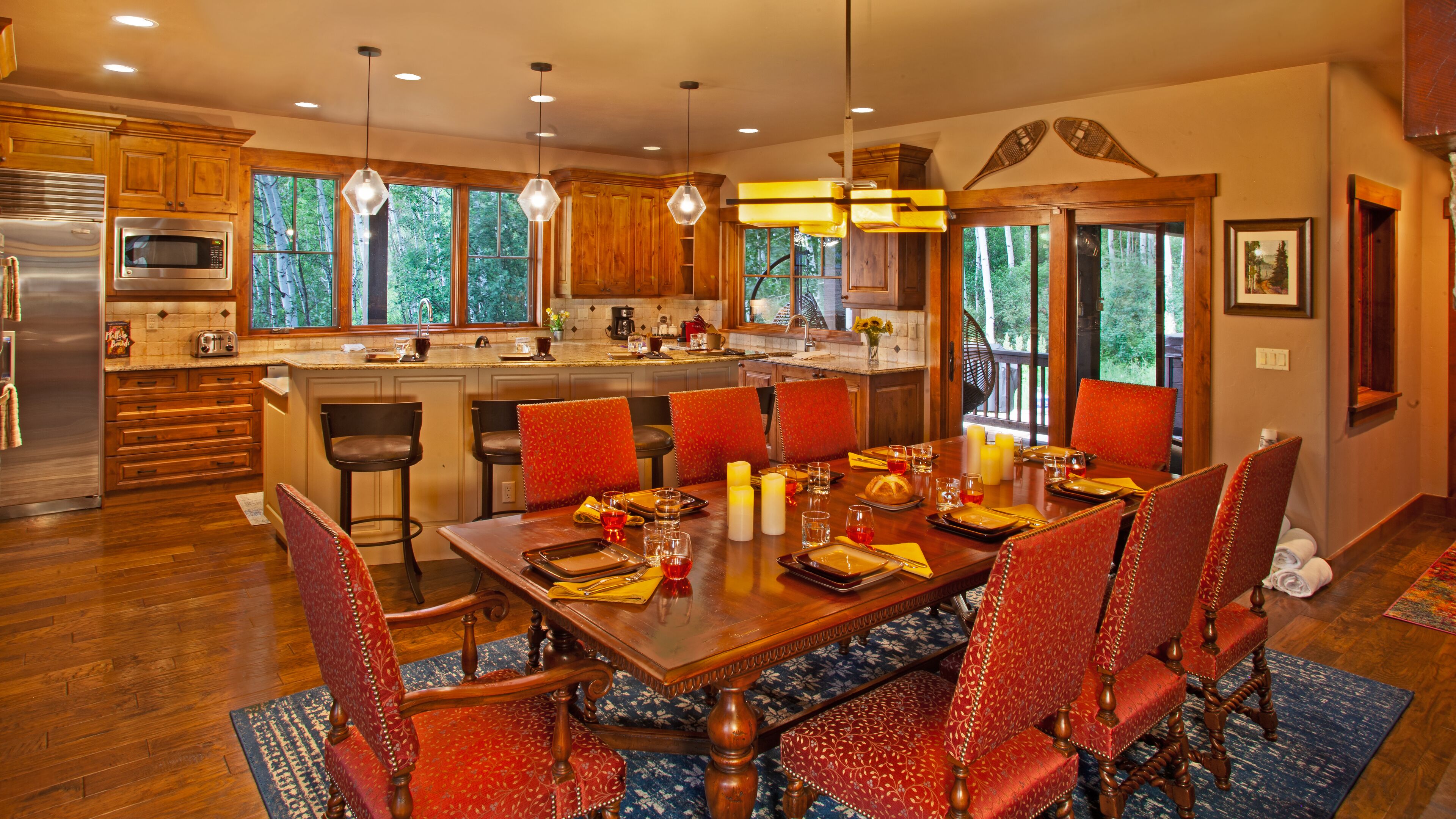 A spacious kitchen with wooden cabinets, a stainless steel refrigerator, and a large island with bar stools.