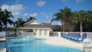 A swimming pool with a fountain, surrounded by palm trees and a white fence. - Glenbrook Lovely 4 Bed Pool/Spa Home! (Clermont)