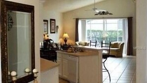 A spacious living area with a kitchen, a dining table, and a large window offering a view. - Glenbrook Lovely 4 Bed Pool/Spa Home! (Clermont)