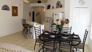 A dining area with a table set for four, surrounded by chairs. A kitchen is visible in the background with a white countertop and various appliances. - Glenbrook Lovely 4 Bed Pool/Spa Home! (Clermont)
