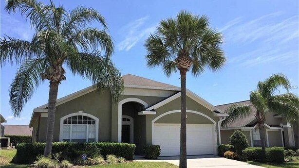 A two-story house with a garage, surrounded by well-maintained lawns and palm trees. - Glenbrook Lovely 4 Bed Pool/Spa Home! (Clermont)