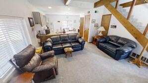 A living room with two leather sofas, a small table, and a wooden beam structure. - LRM Cabin - In Town - Walk to Main Street - WiFi - Satellite - Wood Burning Fire (Red River)