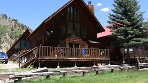 A wooden lodge with a balcony, a sign indicating it is a vacation rental, and a mountain backdrop. - Beaver Lodge - In Town - On the River - Near Copper Chair Lift - Free WiFi - Cab (Red River)