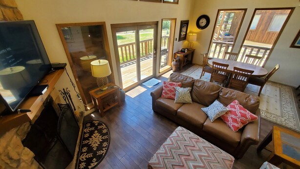 A spacious living room with a brown leather sofa, a television, and a wooden floor. - Beaver Lodge - In Town - On the River - Near Copper Chair Lift - Free WiFi - Cab (Red River)