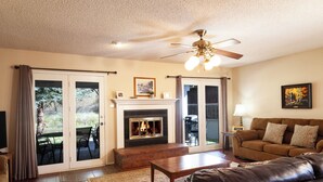 A living room with a fireplace, a leather sofa, a coffee table, and a ceiling fan. - By the River - In Town - On The River - Backyard Fishing Spot - Free WiFi - Cabl (Red River)