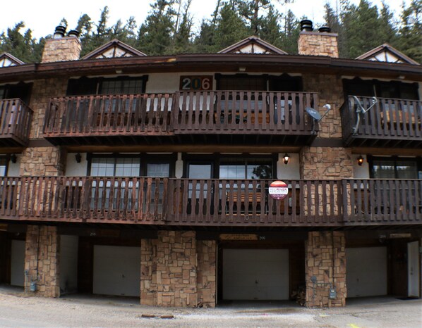A two-story building with a stone facade, numbered 206, featuring balconies and a sign for Redriver Real Estate. - Rose Rock Mountain View - In Town - Pet Friendly - Wood Fireplace - Wifi - Washe (Red River)