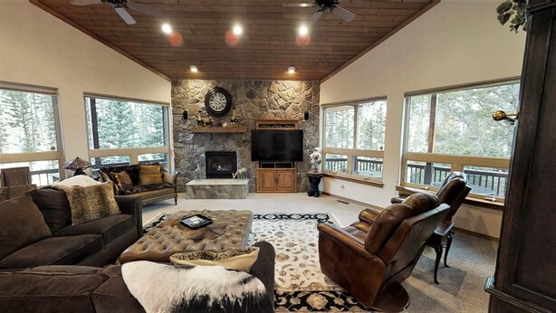 A spacious living room with a stone fireplace, large windows, and a cozy seating area.