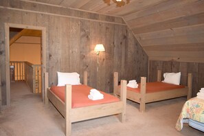 Ein rustikales Zimmer mit zwei hölzernen Betten, einer Holzbalkendecke und einer Lampe.