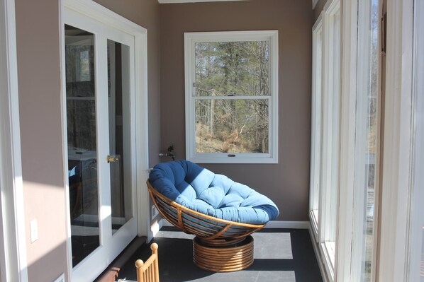 Una habitación con una silla de mimbre, una ventana y una puerta.