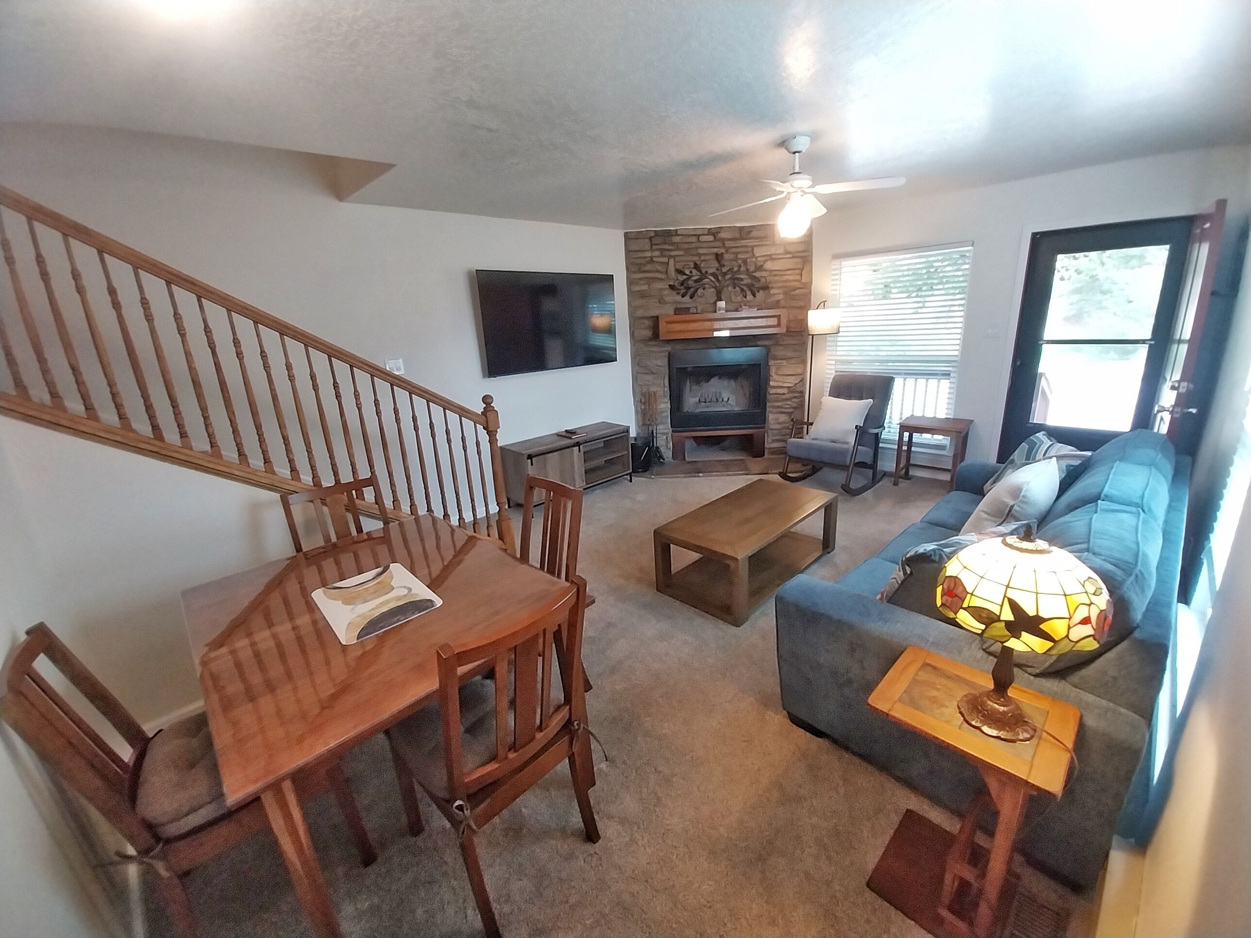 A living room with a fireplace, a sofa, a coffee table, and a dining area with chairs.