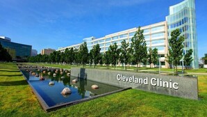 En byggnad med en skylt som visar texten ”Cleveland Clinic”, placerad framför ett välanlagt område med en vattendekoration.