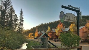 A sign for Valley Condominiums with a playground and a pond in the foreground.