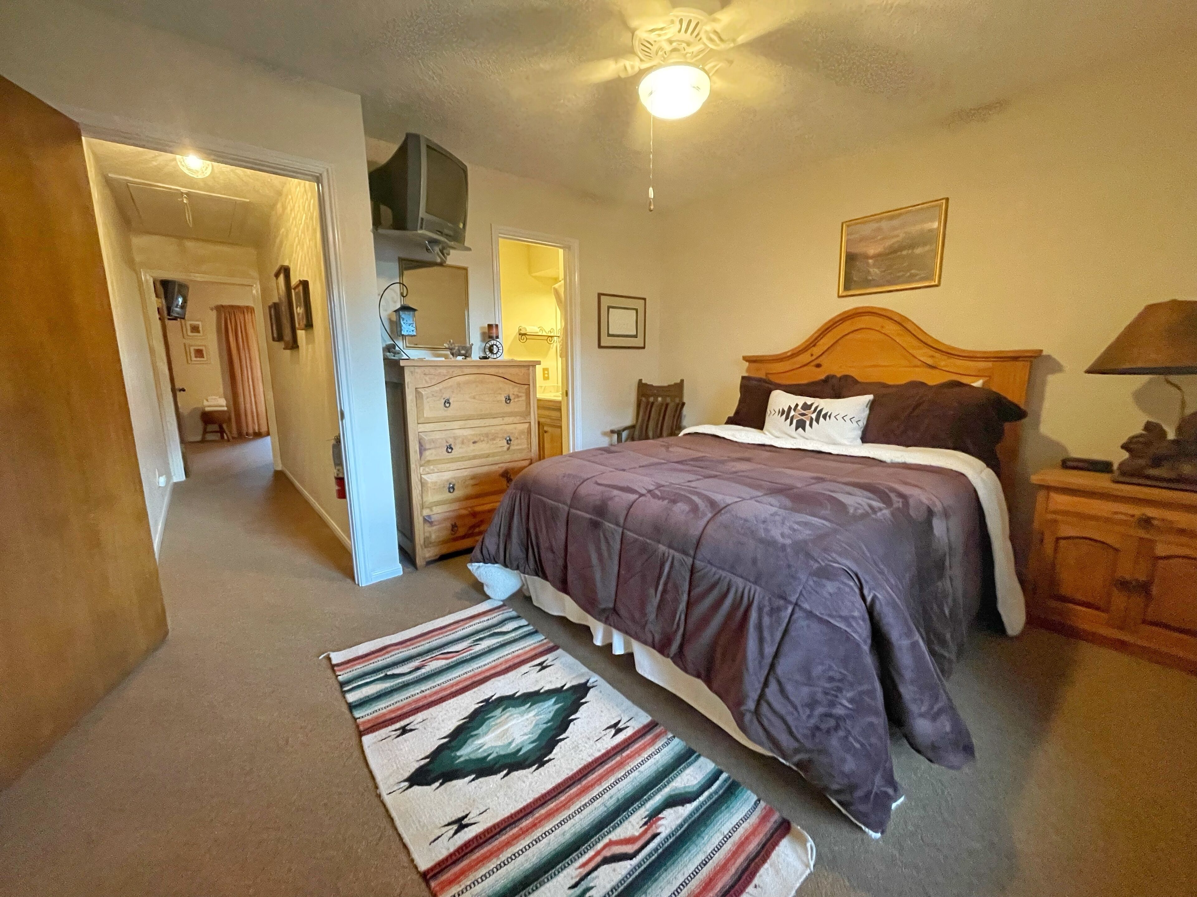 A bedroom with a bed, dresser, and a mirror.