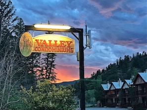 Señal de Valley Condominiums con montañas al fondo y un atardecer.