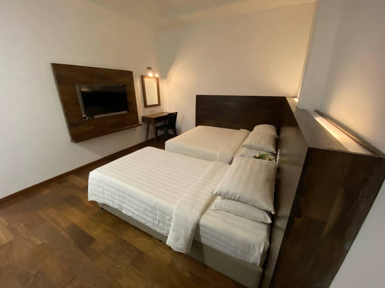 A hotel room with a bed, a desk, a TV mounted on the wall, and a mirror.