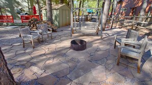 A patio area with stone flooring, wooden benches, a fire pit, and a swing set. - Mountain Living at its Finest! (Pinetop)