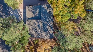 An aerial view of a building with a distinct geometric roof, surrounded by trees and a paved area. - Mountain Living at its Finest! (Pinetop)