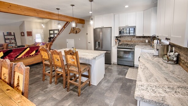 A spacious kitchen with white cabinets, a granite countertop, and a wooden dining area. - Mountain Living at its Finest! (Pinetop)