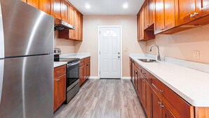 A kitchen with wooden cabinets, stainless steel appliances, and a white door.