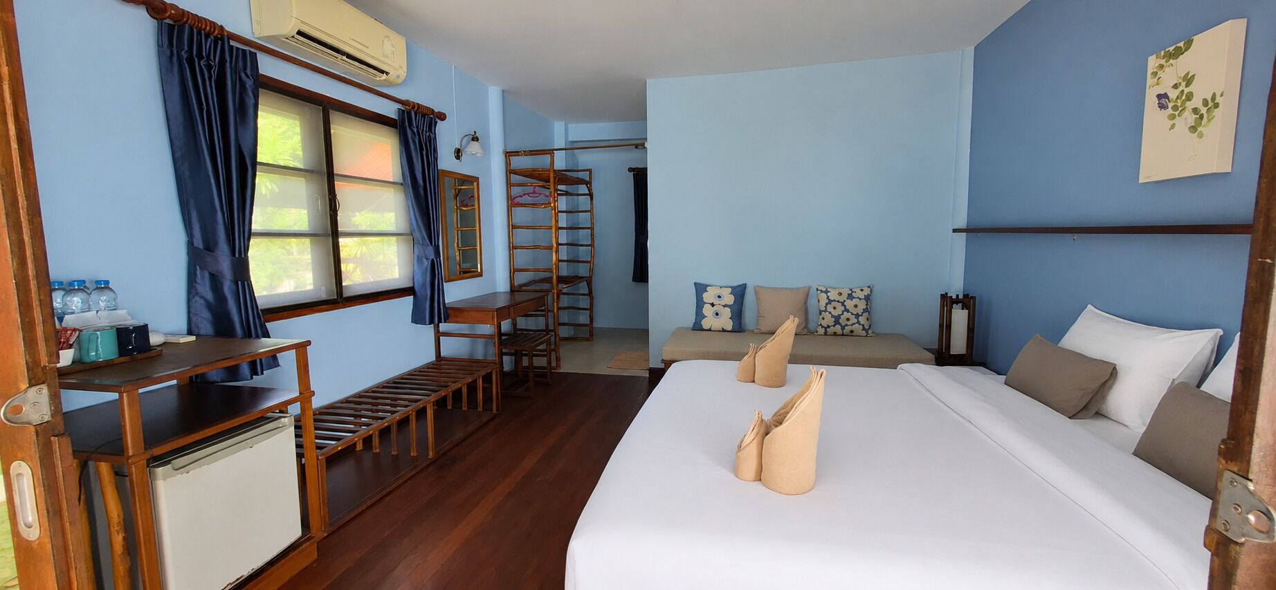 Habitación de hotel con cama, escritorio, silla, mesita, escalera y ventana con cortinas.