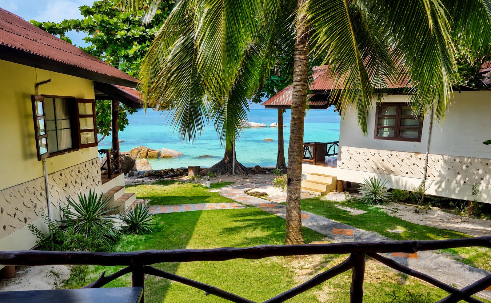 A tropical resort with a pool, palm trees, and a view of the ocean.