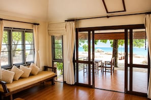 Una habitación con un banco de madera y vistas a una playa a través de amplios ventanales.