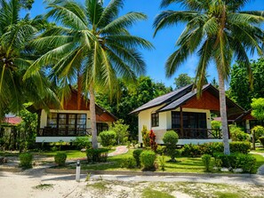 Un resort con dos edificios principales, rodeado de palmeras y jardines cuidados.
