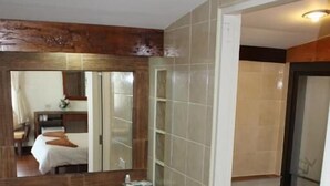 Casa de banho com toucador de madeira, lavatório branco e sanita.
