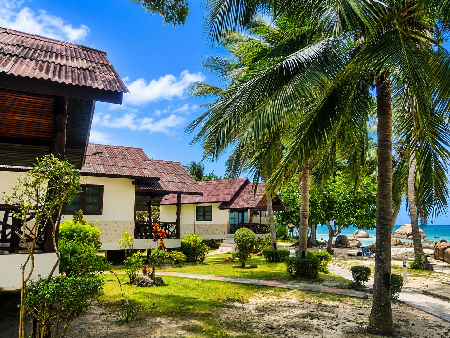 A beachfront property with a two-story building, a covered patio, and a view of the ocean.