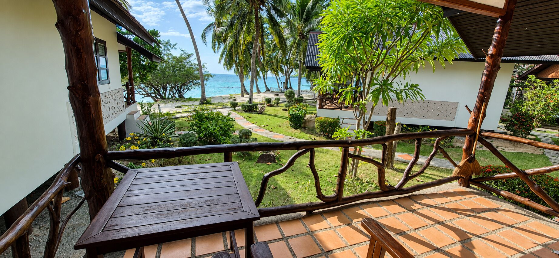 A wooden deck with a view of a garden and the sea.