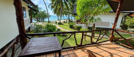 A wooden deck with a view of a garden and the sea.