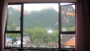 Une pièce dotée d’une grande fenêtre donnant sur un paysage montagneux, avec un bâtiment de style traditionnel.