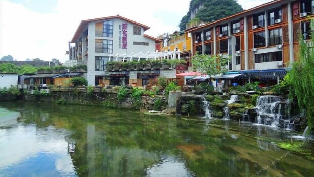 Un hôtel situé au bord de la rivière, avec plusieurs étages, des espaces de détente en plein air et une petite cascade.