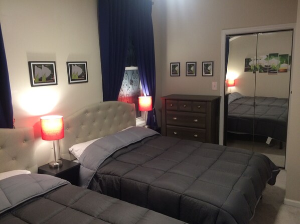 A bedroom with two beds, a dresser, and a mirror.