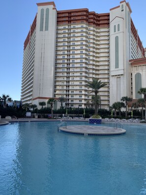 Un hotel grande con varios balcones, piscina y palmeras.