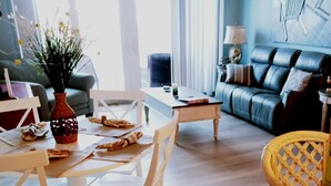 Ein modernes Wohnzimmer mit Essbereich, ausgestattet mit einer Couch, einem Couchtisch und einem Esstisch mit Stühlen.