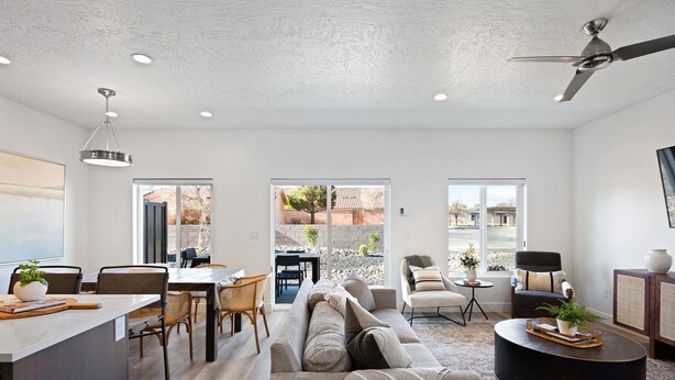 A modern living room with a sofa, dining area, and a ceiling fan.