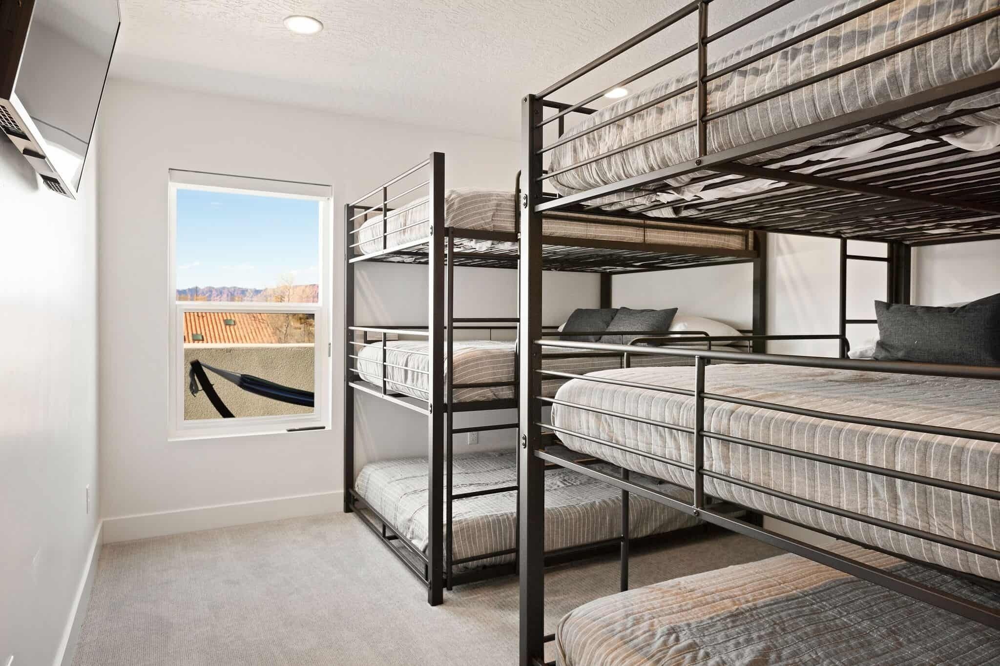 Une chambre avec des lits superposés et une fenêtre donnant sur une structure en bois à l’extérieur.