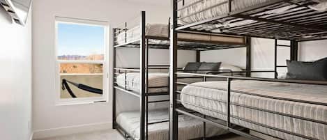 Une chambre avec des lits superposés et une fenêtre donnant sur une structure en bois à l’extérieur.