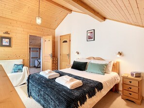 A cozy bedroom with a bed, bedside tables, a chair, and a wardrobe.