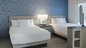 Habitación de hotel con dos camas, televisión, lámpara y ventana.
