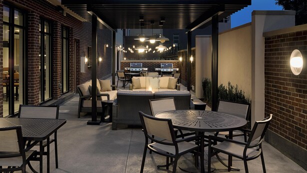 An outdoor patio area with a covered seating area, a grill, and a round table with chairs. - Hyatt House Columbus OSU / Short North (Columbus)