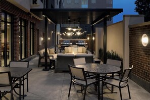An outdoor patio area with a covered seating area, a grill, and a round table with chairs. - Hyatt House Columbus OSU / Short North (Columbus)