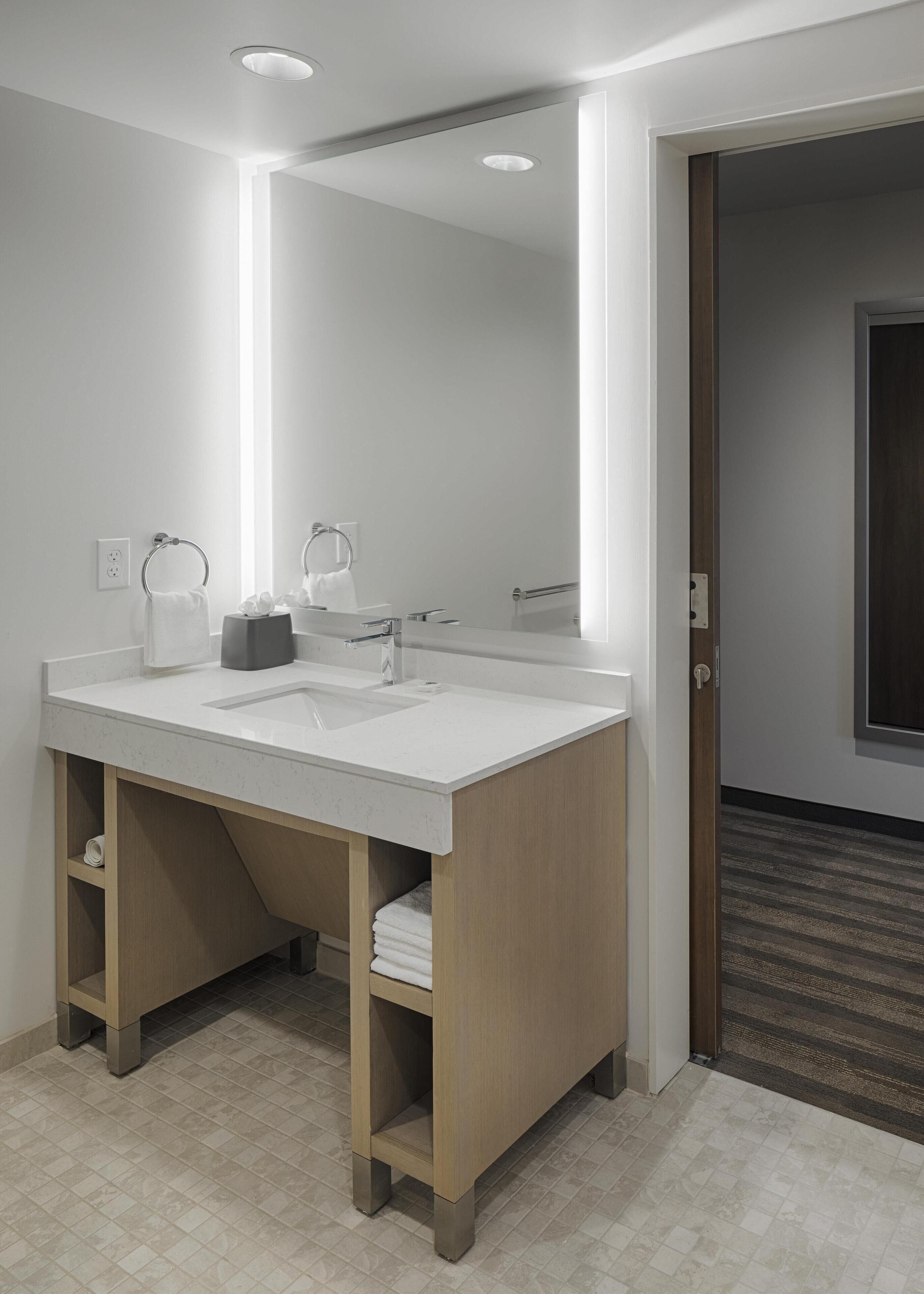 Un baño moderno con un espejo grande, dos lavamanos y un mueble de tocador de madera.